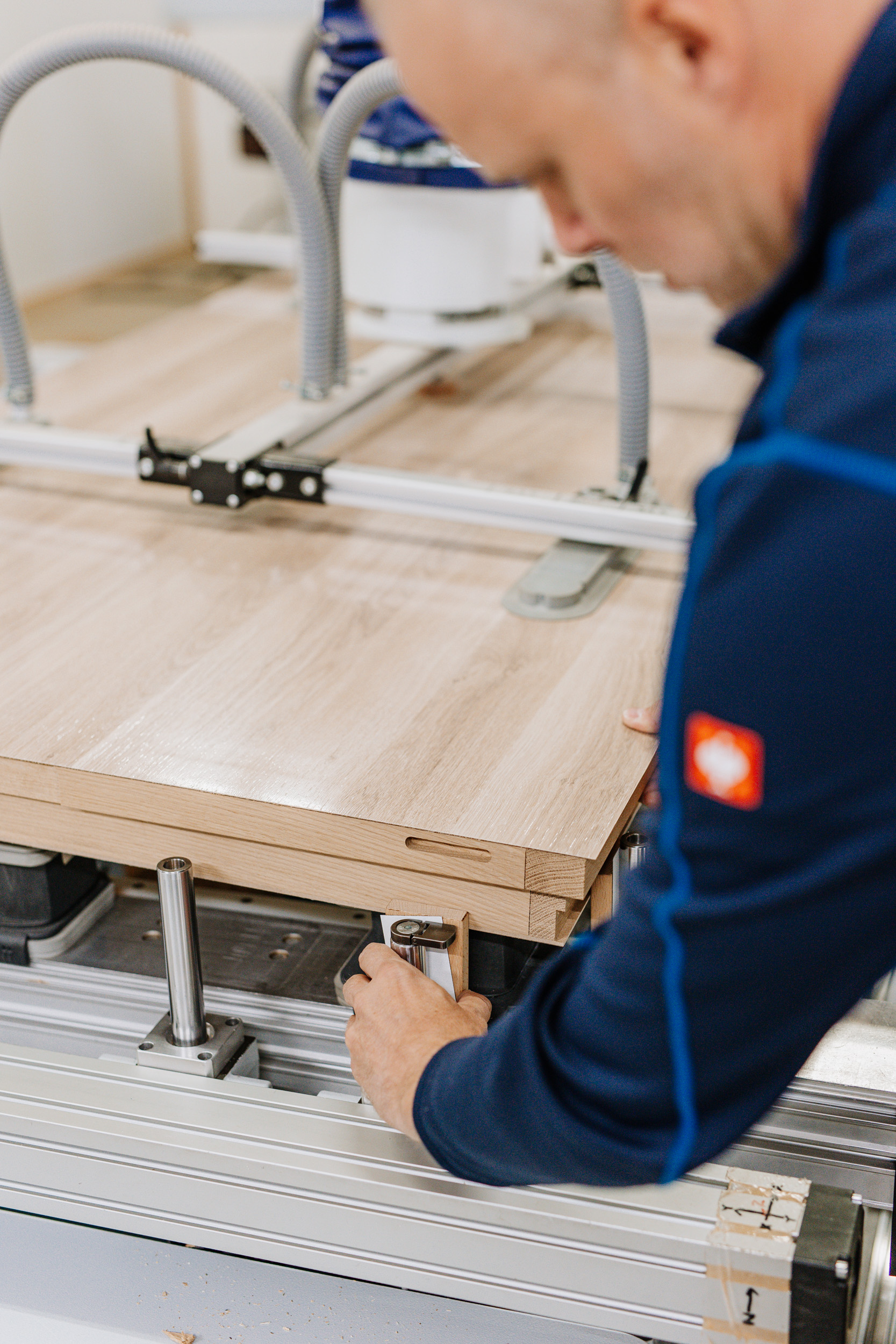 Ein Mitarbeiter arbeitet mit einer Maschine, in der Holz eingespannt ist.