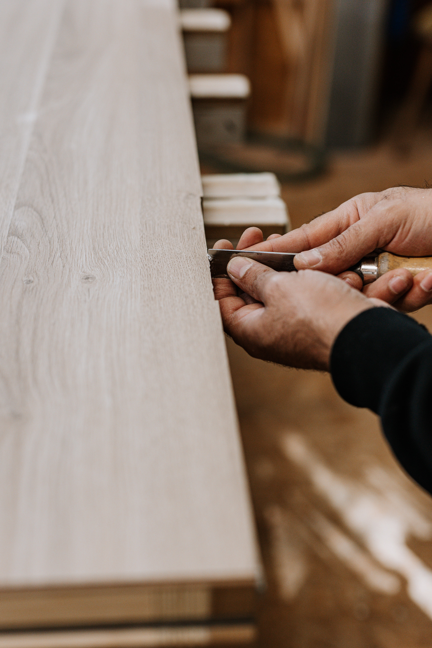 Ein Mitarbeiter hobelt Holz an einem Holzbrett.