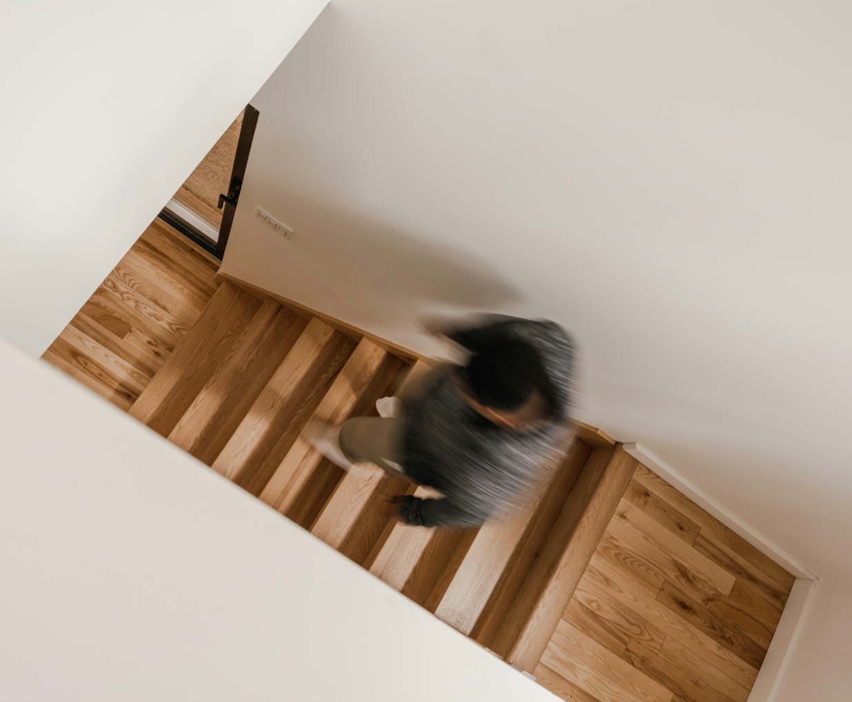 Ein Mann geht eine Holztreppe hinunter, von oben fotografiert.