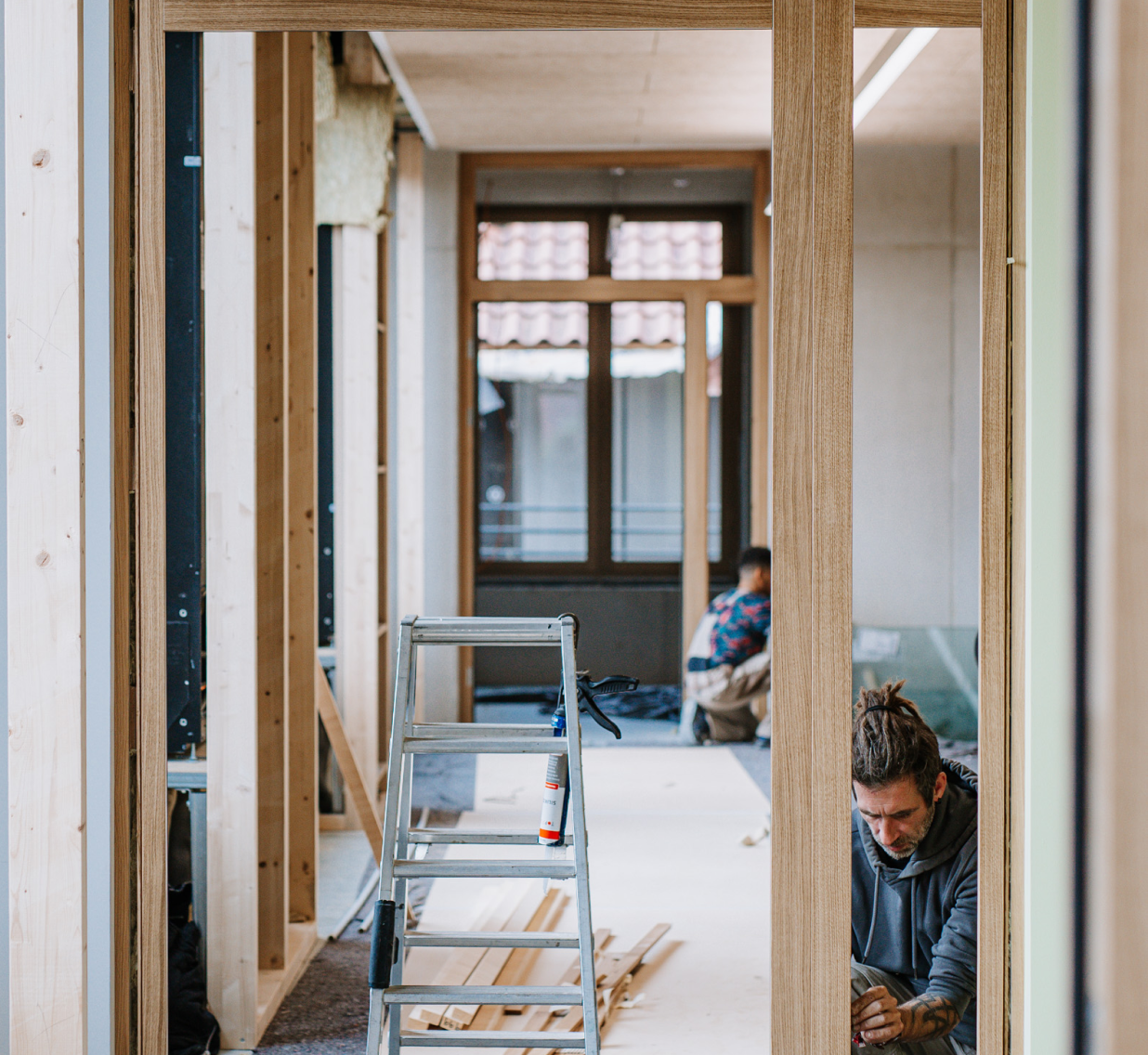 Zwei Mitarbeiter bauen Holztürrahmen ein.