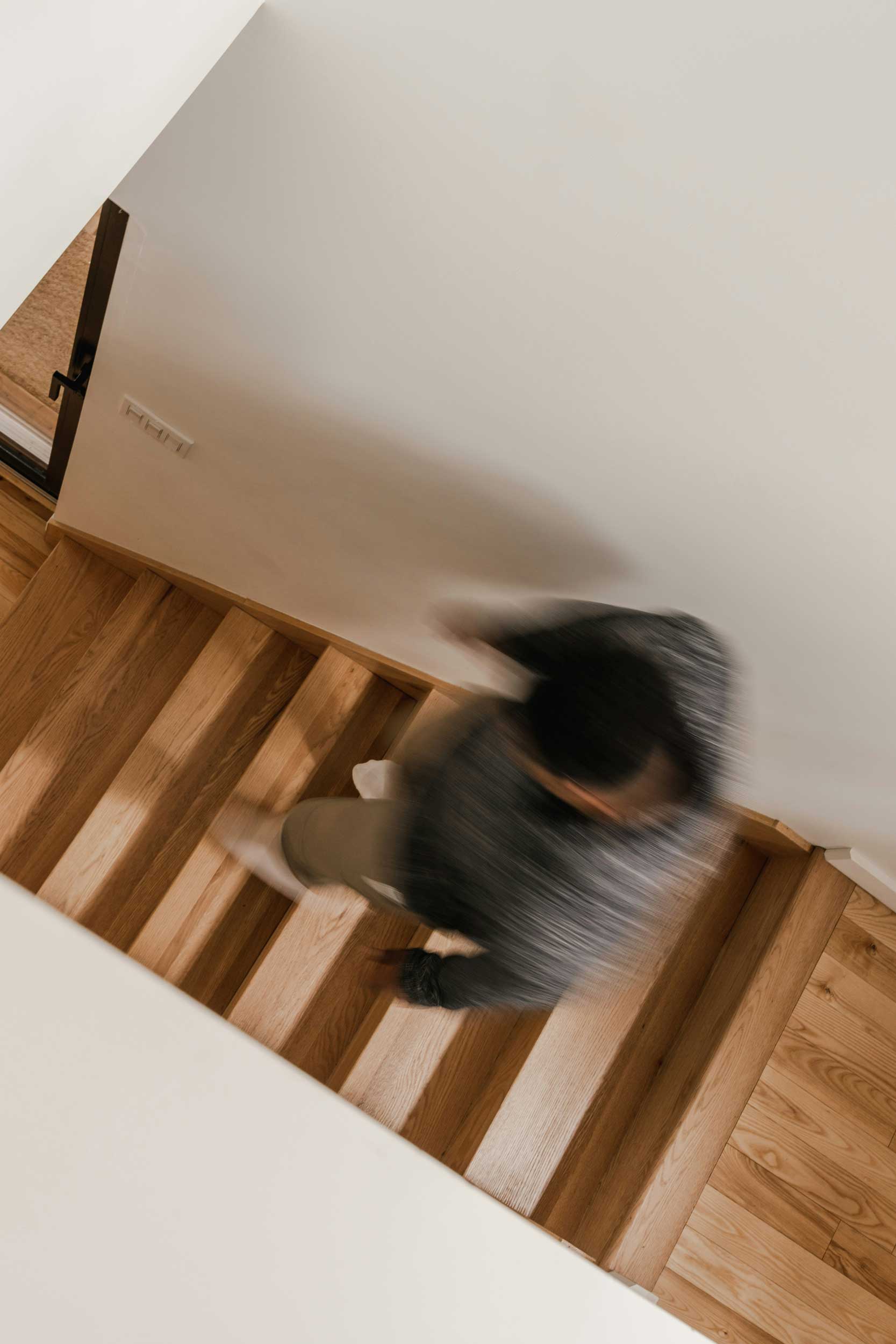 Ein Mann geht eine Holztreppe hinunter, von oben fotografiert.