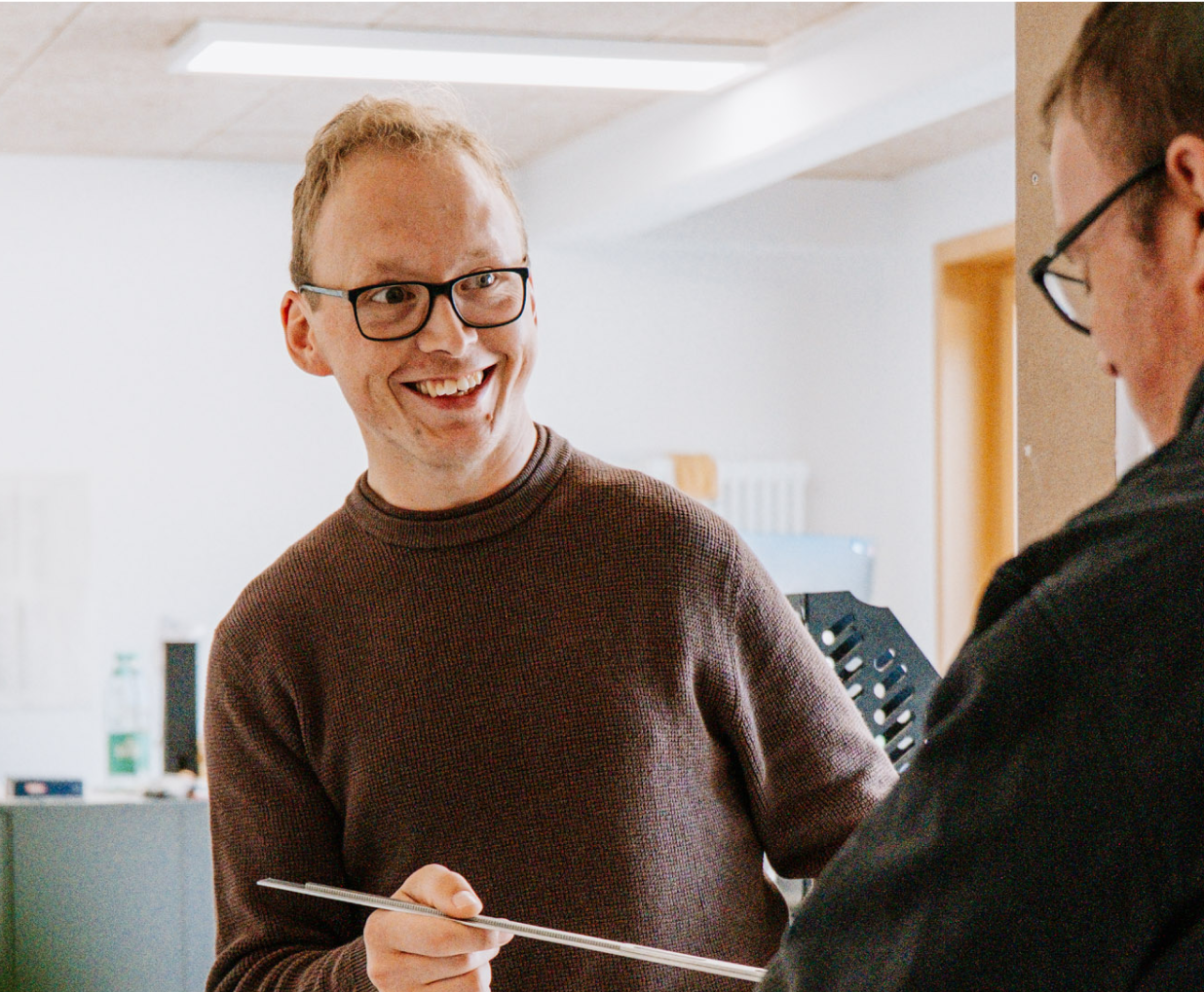 Zwei Mitarbeiter sprechen über verschiedene Pläne, wobei der eine Mitarbeiter im Fokus ist.