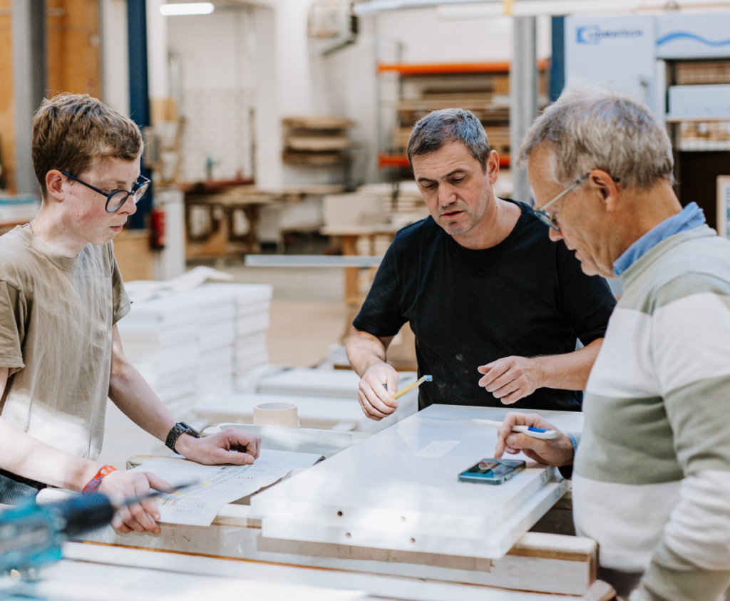 Drei Mitarbeiter tauschen sich über Pläne aus.